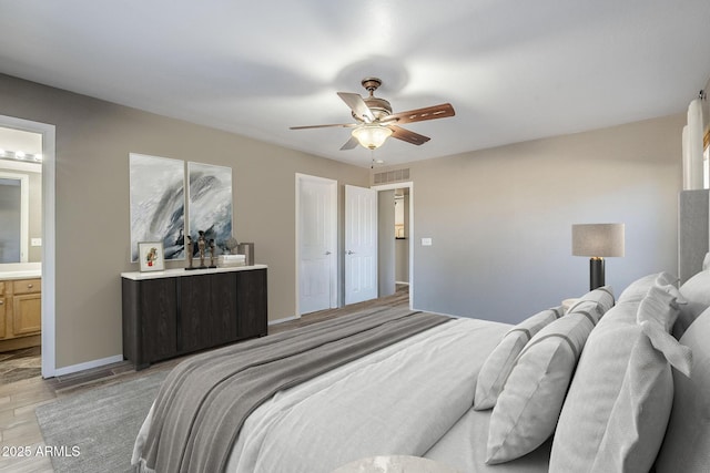 bedroom featuring ceiling fan, ensuite bath, and light wood-type flooring