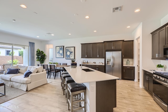 kitchen with visible vents, appliances with stainless steel finishes, open floor plan, light countertops, and a sink