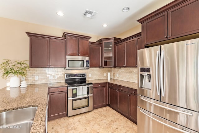 3443 E Jasper Dr, Gilbert, AZ 85296 - kitchen featuring appliances with stainless steel finishes, light stone counters, decorative backsplash, glass insert cabinets, and recessed lighting