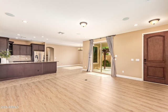 3443 E Jasper Dr, Gilbert, AZ 85296 - unfurnished living room featuring arched walkways, baseboards, light wood-type flooring, recessed lighting, and a chandelier