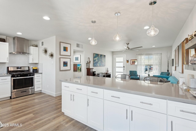 2129 W Indianola Ave, Phoenix, AZ 85015 - kitchen featuring wall chimney exhaust hood, gas range, recessed lighting, ceiling fan, and white cabinets