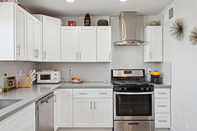 2129 W Indianola Ave, Phoenix, AZ 85015 - kitchen featuring wall chimney exhaust hood, appliances with stainless steel finishes, white cabinets, and decorative backsplash
