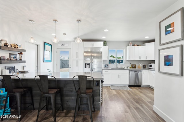 2129 W Indianola Ave, Phoenix, AZ 85015 - kitchen with appliances with stainless steel finishes, a sink, a kitchen breakfast bar, white cabinets, and wood finished floors