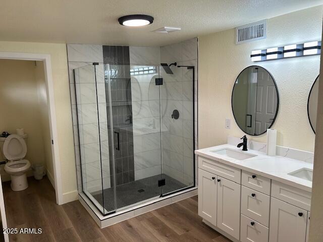 full bathroom with visible vents, a stall shower, wood finished floors, and a sink