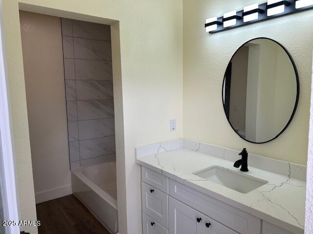 full bath with vanity, wood finished floors, and baseboards