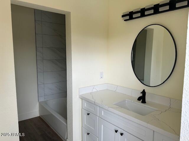 full bath featuring vanity, a tub to relax in, and wood finished floors