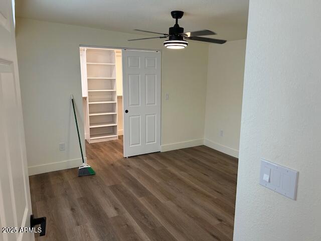 spare room featuring baseboards, dark wood finished floors, and a ceiling fan