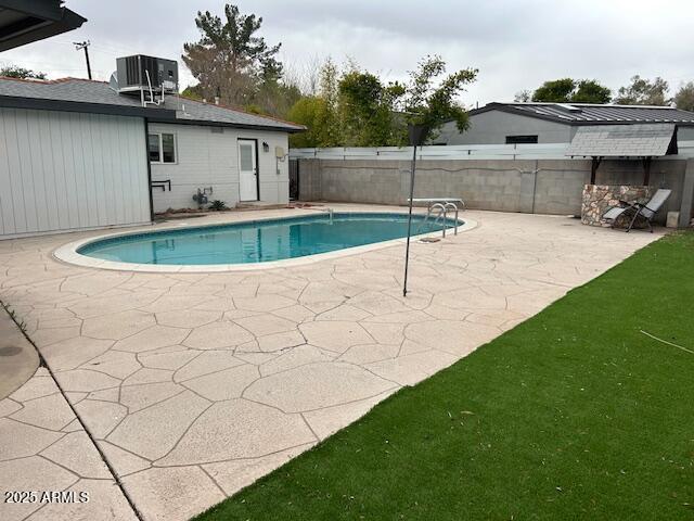 view of swimming pool featuring a fenced backyard, a fenced in pool, central AC, and a patio