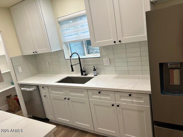 kitchen with a sink, refrigerator with ice dispenser, white cabinets, and dishwasher