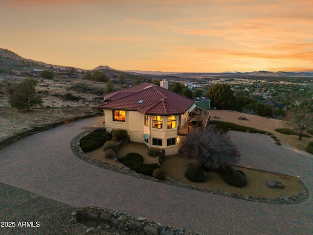 view of front of property featuring curved driveway, a mountain view, a tile roof, and stucco siding