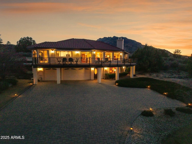 view of front of house with a chimney, stucco siding, a garage, decorative driveway, and a mountain view