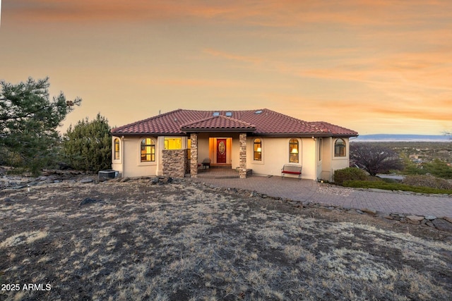 mediterranean / spanish-style home with stone siding, stucco siding, and a tiled roof