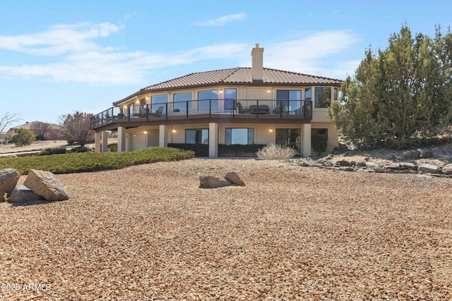 back of property featuring stucco siding, a tile roof, and a chimney