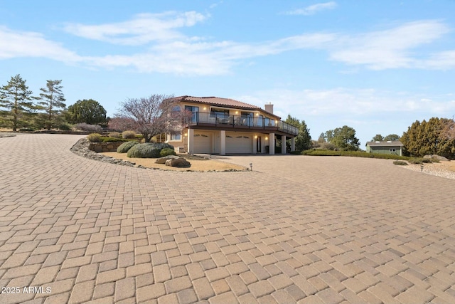 view of front facade featuring driveway, a chimney, and a garage