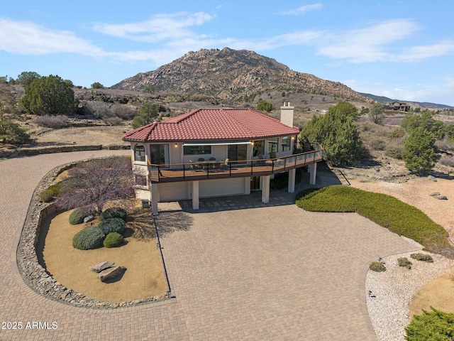 view of front of home with a mountain view, decorative driveway, a chimney, and a tiled roof