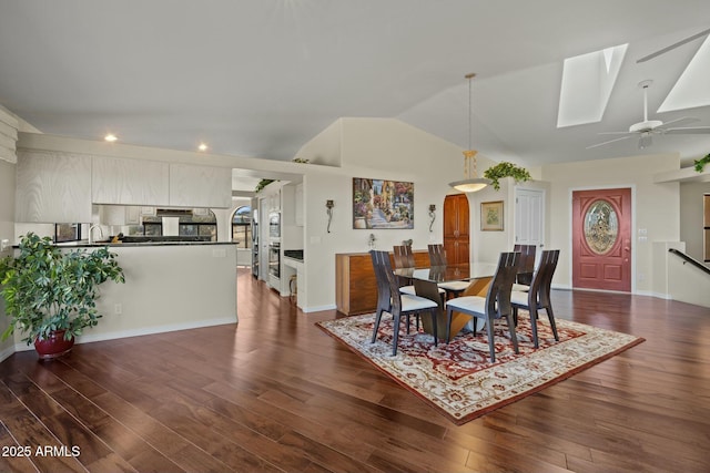 dining room with baseboards, lofted ceiling with skylight, and dark wood-type flooring