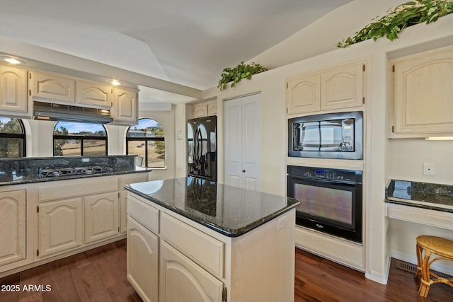 kitchen featuring dark stone countertops, black appliances, dark wood finished floors, and vaulted ceiling