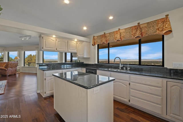 kitchen featuring dark stone countertops, a peninsula, dark wood-style flooring, a sink, and white cabinets