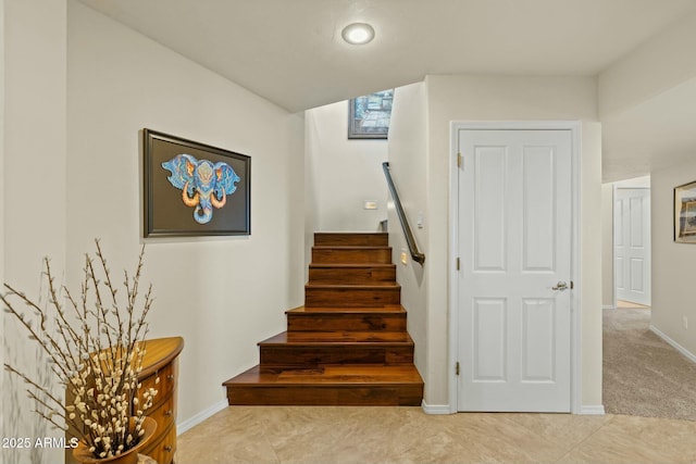 staircase with tile patterned floors, baseboards, and carpet