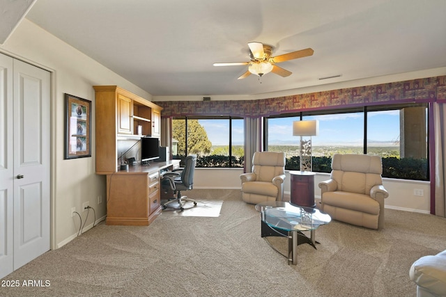 living area featuring light colored carpet, baseboards, and ceiling fan