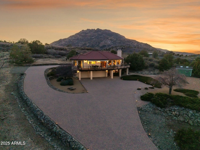 view of front of property featuring decorative driveway, a mountain view, and a chimney