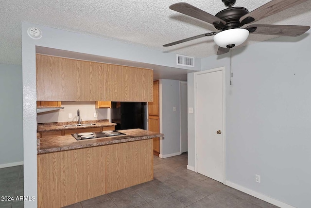 kitchen featuring ceiling fan, sink, a textured ceiling, light brown cabinetry, and black appliances