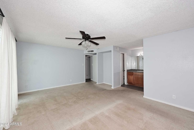 unfurnished living room featuring light carpet, ceiling fan, and a textured ceiling