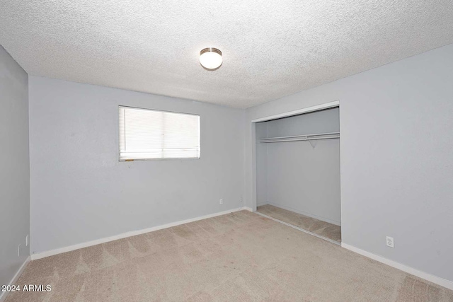 unfurnished bedroom featuring a closet, light colored carpet, and a textured ceiling