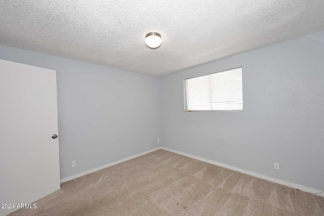 unfurnished room with carpet and a textured ceiling