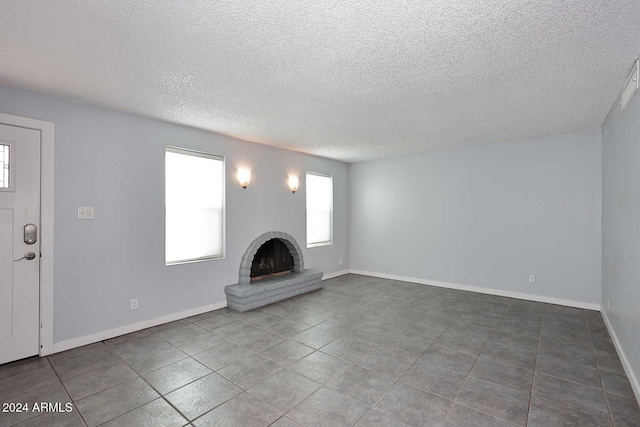 unfurnished living room featuring tile patterned floors, a textured ceiling, and a brick fireplace