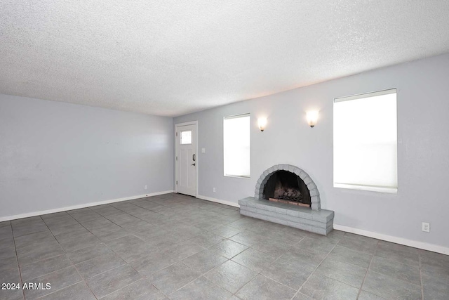 unfurnished living room with a fireplace and a textured ceiling