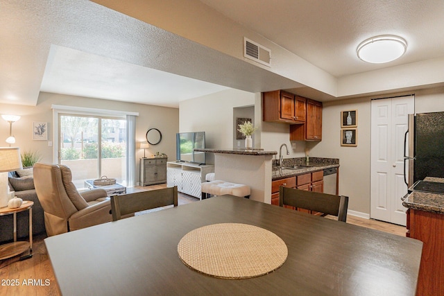 dining area featuring visible vents, baseboards, a textured ceiling, and light wood-style flooring