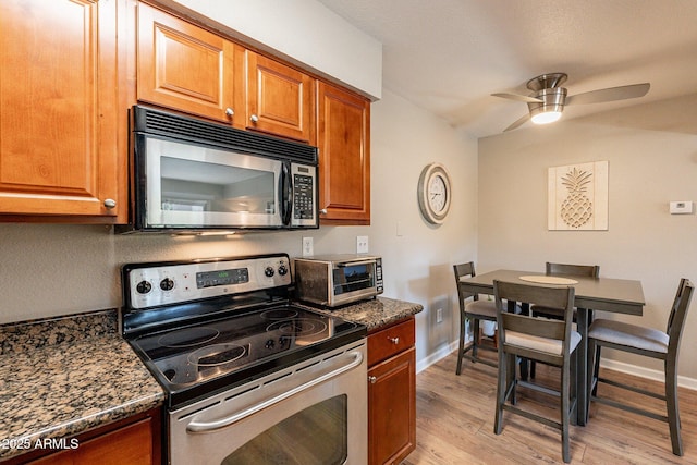 kitchen with light wood finished floors, a toaster, brown cabinets, electric range, and a ceiling fan