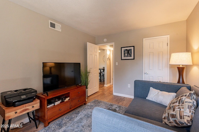 living room featuring visible vents, baseboards, and wood finished floors