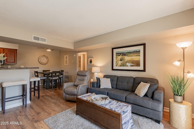 living room with visible vents, baseboards, and light wood-style floors