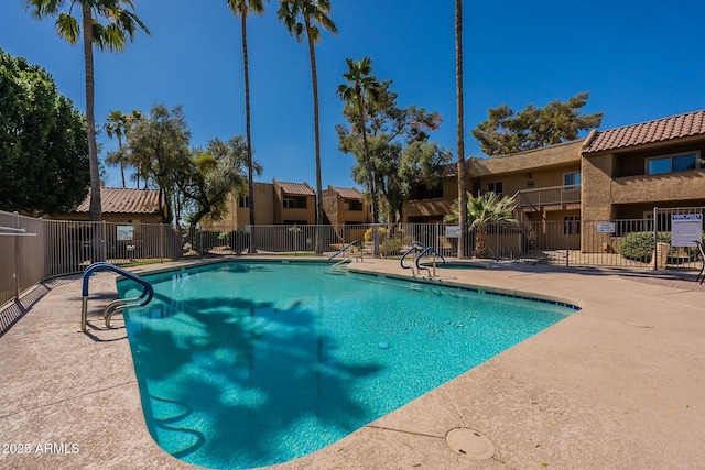 community pool featuring a patio area, fence, and a residential view