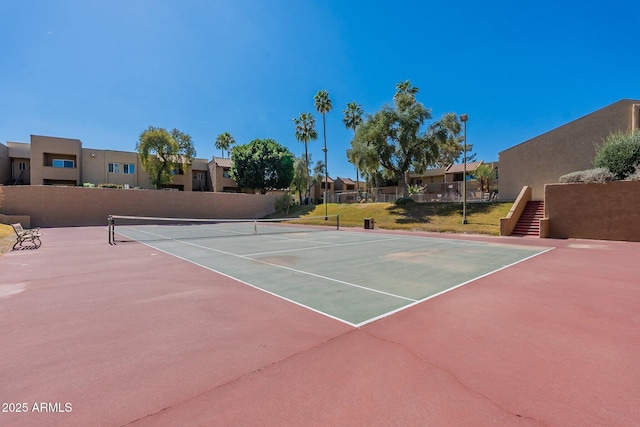 view of tennis court featuring a residential view and fence