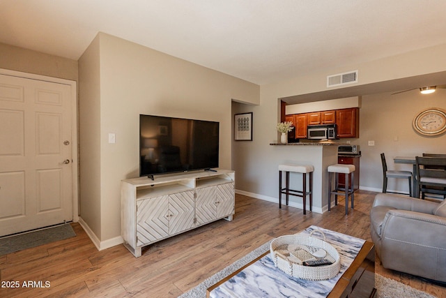 living room with baseboards, visible vents, and light wood-type flooring