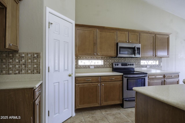 kitchen featuring light tile patterned flooring, light countertops, backsplash, and stainless steel appliances
