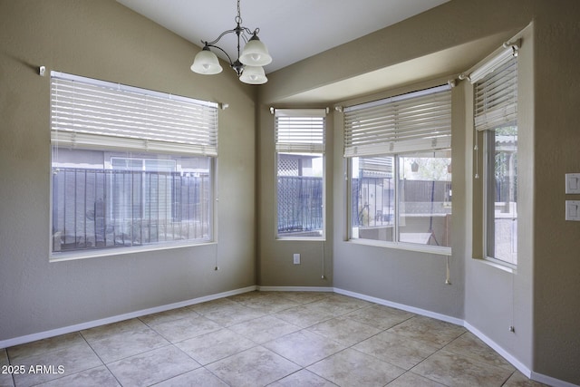 empty room with light tile patterned floors, baseboards, a notable chandelier, and a textured wall
