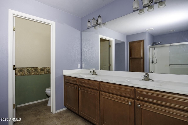 bathroom featuring a sink, toilet, double vanity, and a shower with shower door