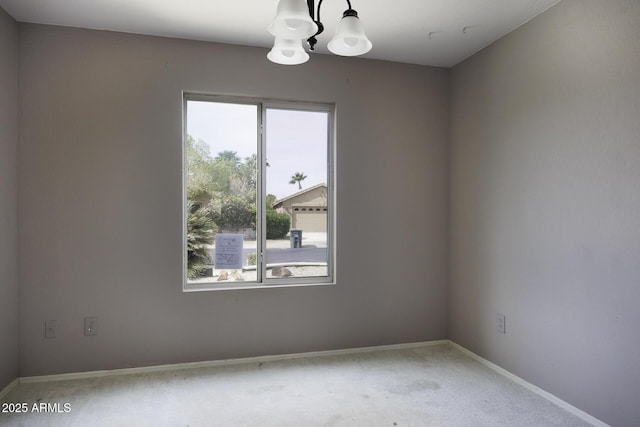 spare room featuring light carpet, baseboards, an inviting chandelier, and a healthy amount of sunlight