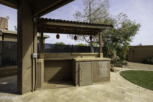view of patio featuring an outdoor kitchen and fence