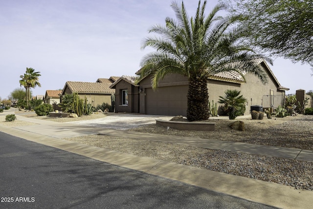 single story home with a tiled roof, an attached garage, driveway, and stucco siding