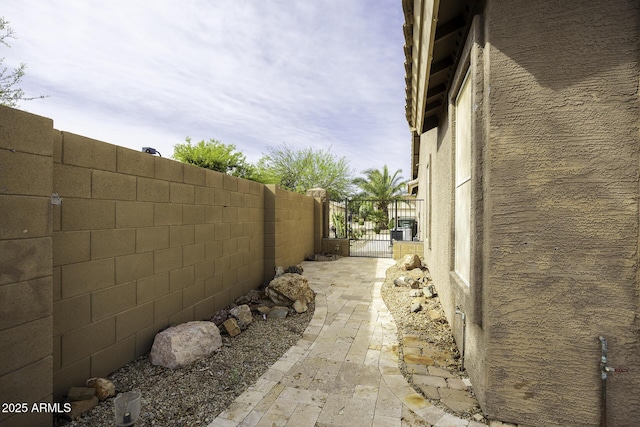 view of property exterior with stucco siding, fence, and a gate