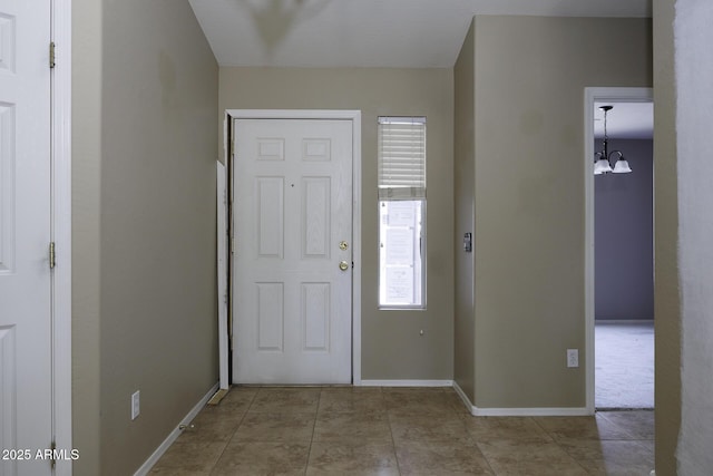 entrance foyer with a chandelier and baseboards