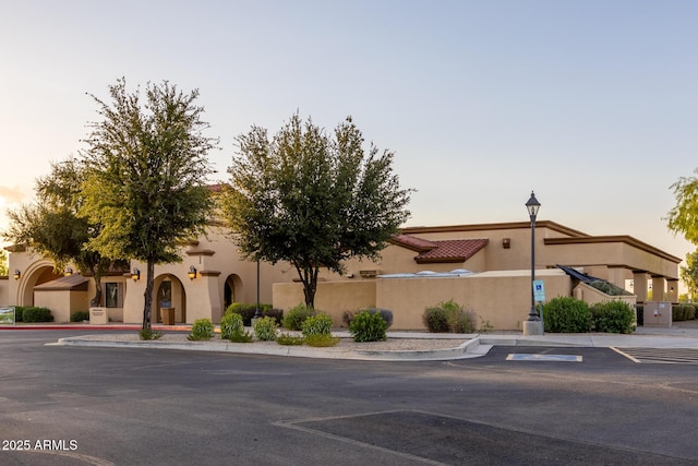 view of front of house with a tiled roof, uncovered parking, and stucco siding