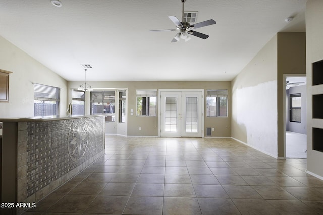 interior space featuring visible vents, baseboards, dark tile patterned floors, ceiling fan with notable chandelier, and lofted ceiling