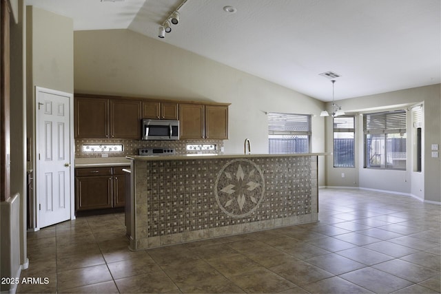 kitchen featuring visible vents, dark tile patterned floors, stainless steel microwave, vaulted ceiling, and backsplash