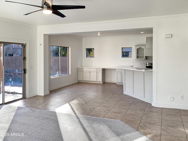 kitchen with ceiling fan, stove, light tile patterned floors, and ornamental molding